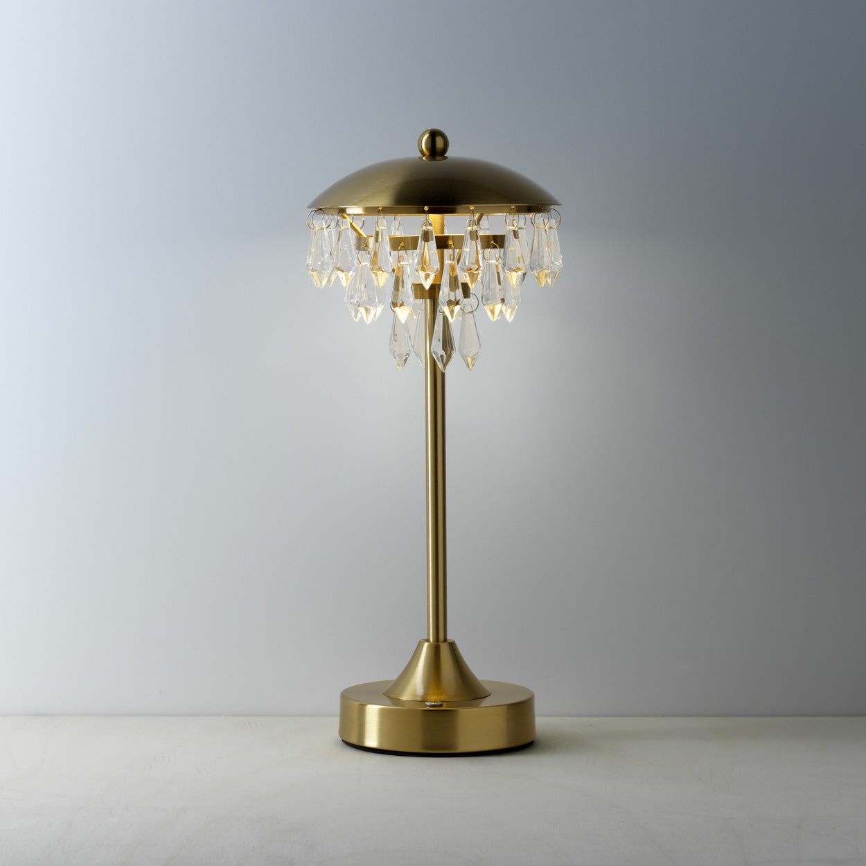 Gold table lamp with crystal accents on a plain background