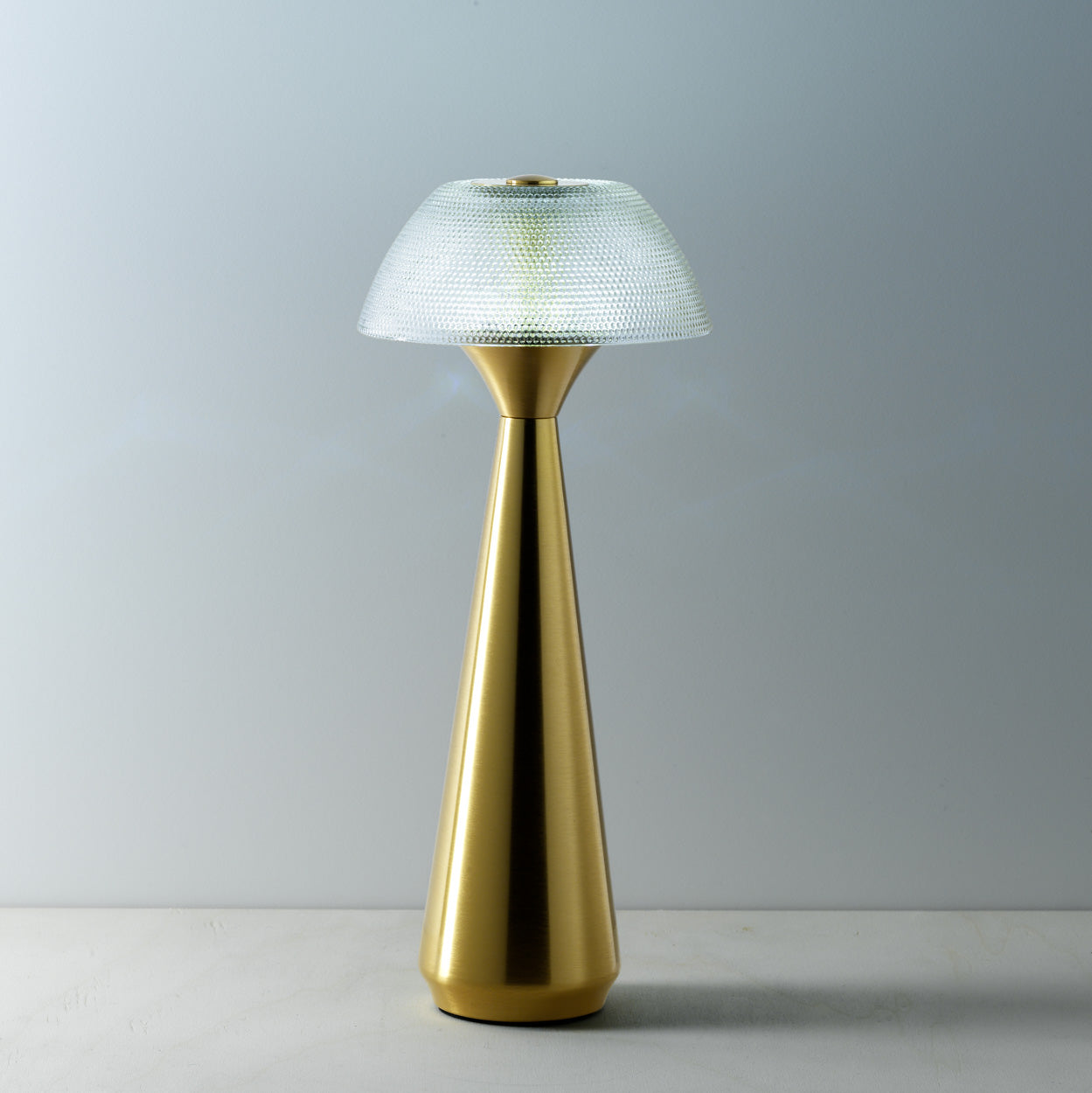 Gold table lamp with textured shade on a neutral background