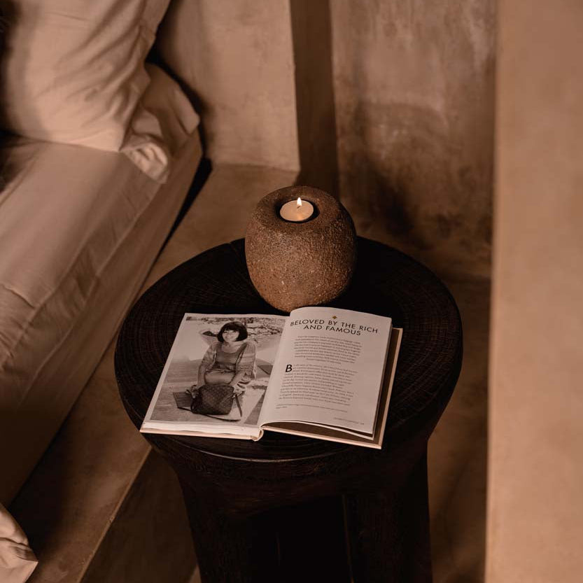 Small round table with a candle holder and open book in a dimly lit room