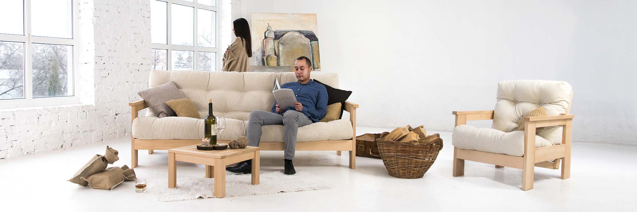 Wooden sofa bed with cream mattress, armchair and wooden coffee table in Scandinavian style