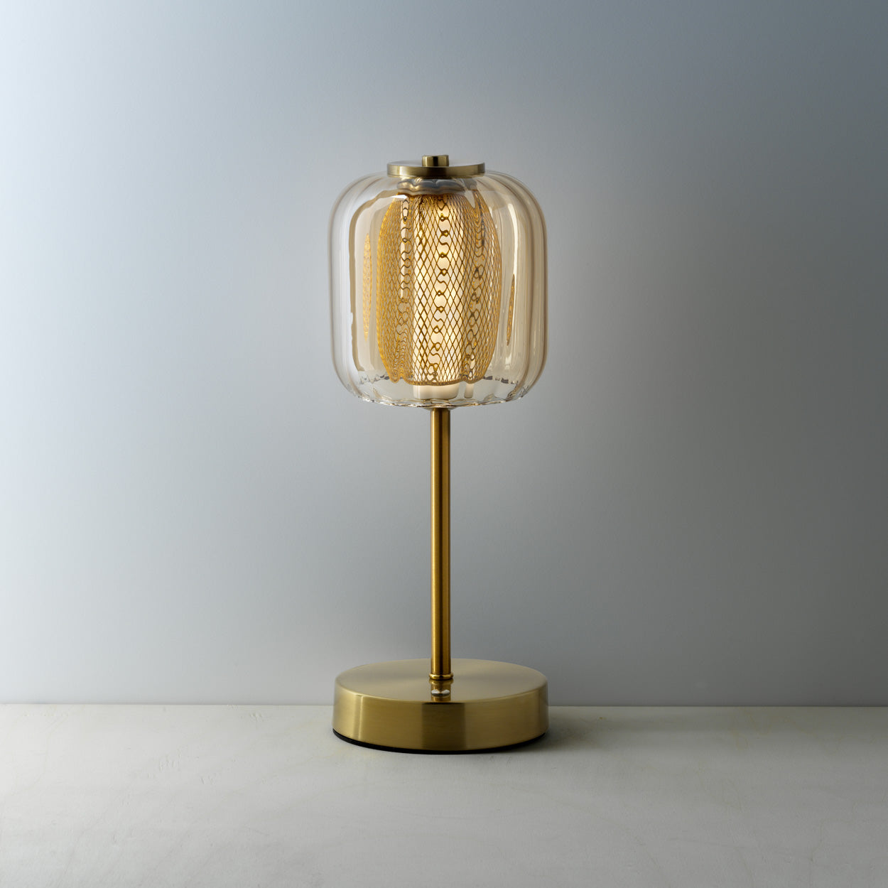 Gold table lamp with a textured glass shade on a gray background