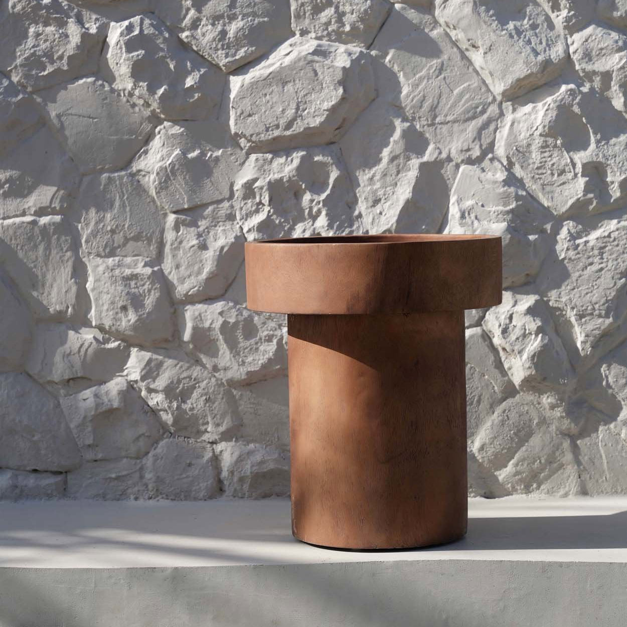 Natural colour side table against a stone wall