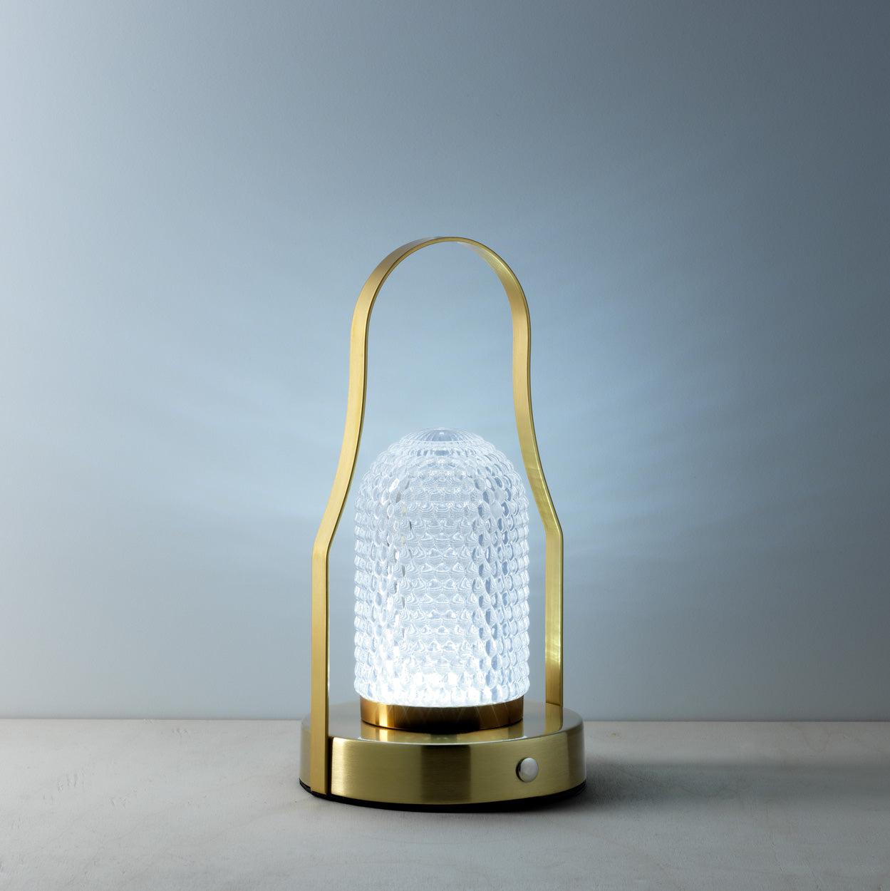 Decorative lamp with textured glass shade and gold metal frame on a neutral background