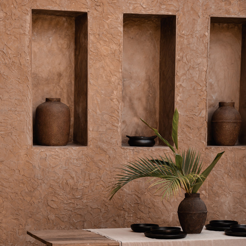 Corner with stone walls, a wooden table, and brown vases