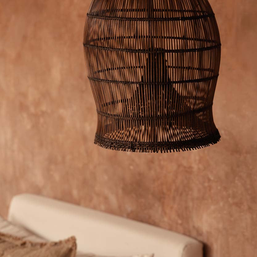Woven bamboo pendant light hanging against a textured wall.