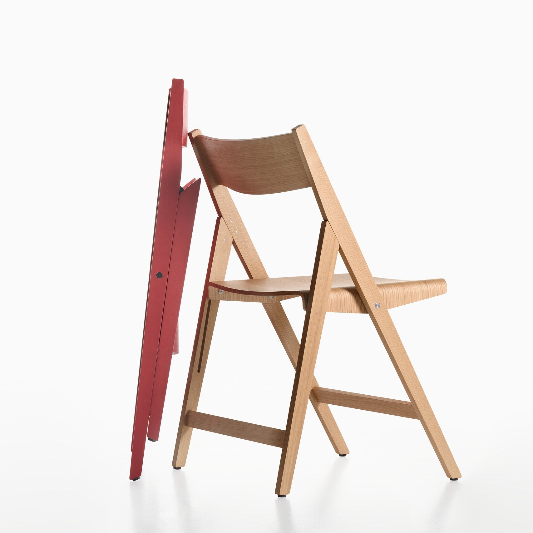 Two THEO wooden chairs, one red and one natural, on a white background