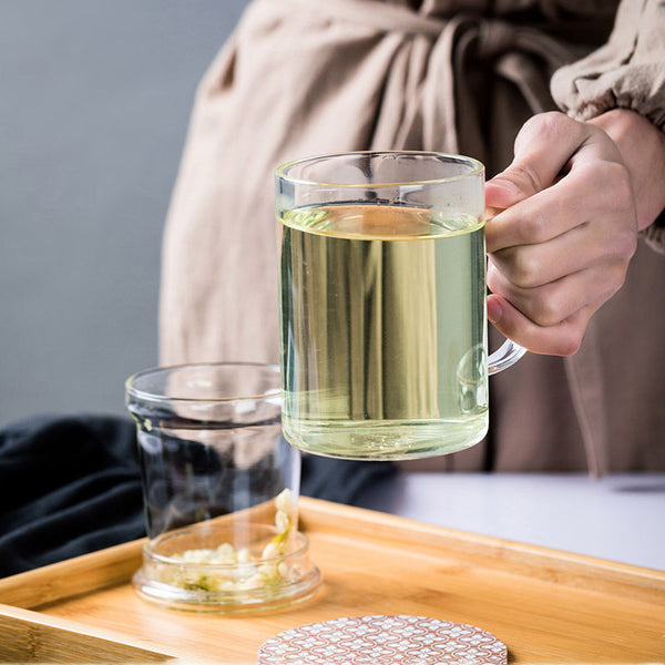 Bicchiere di vetro di tè con infusore e tè alle erbe su un tavolo